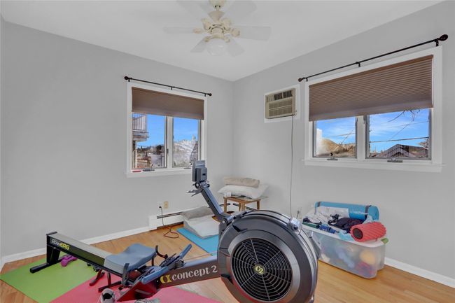 Workout area featuring ceiling fan, hardwood / wood-style floors, a baseboard heating unit, and a wall mounted air conditioner | Image 23