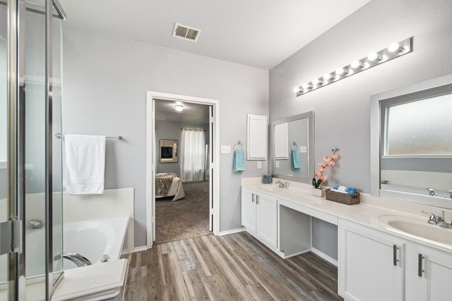 Bathroom featuring visible vents, a bath, a sink, double vanity, and wood finished floors | Image 26