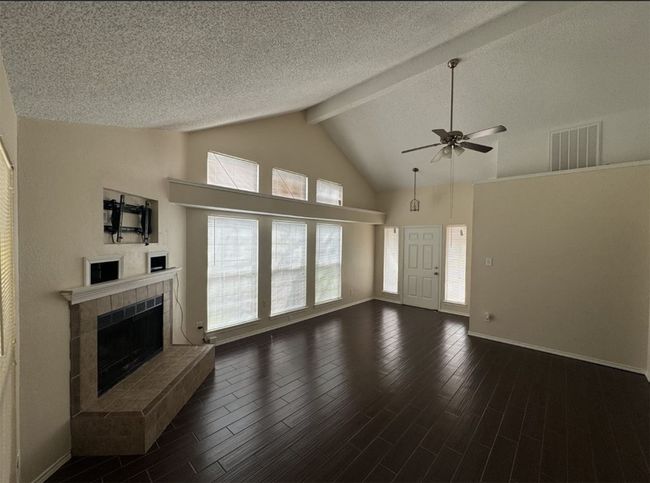 Unfurnished living room featuring high vaulted ceiling, dark hardwood / wood-style floors, beam ceiling, and a tile fireplace | Image 5