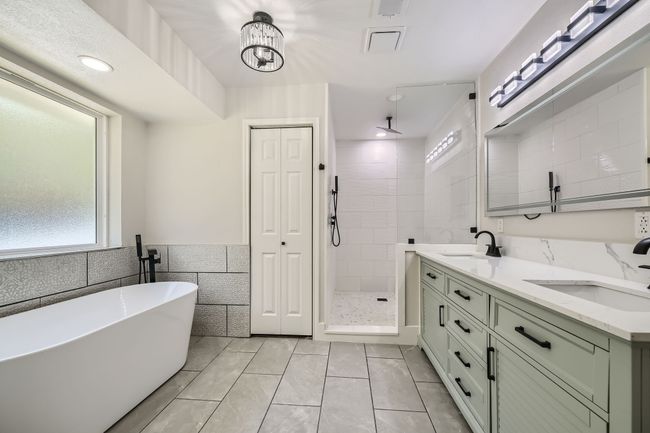 Bathroom with tile walls, a stall shower, tile patterned floors, and a sink | Image 18