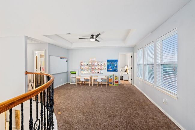 Recreation room with a raised ceiling, carpet, and a ceiling fan | Image 24