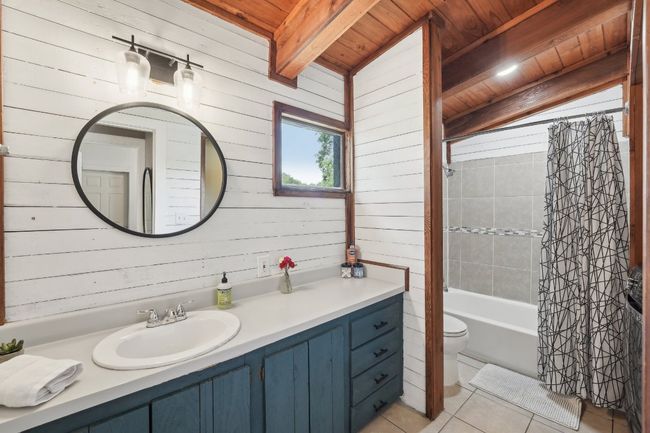 Bathroom featuring wood ceiling with exposed beams, tile patterned floors, wood walls, vanity, and toilet | Image 20