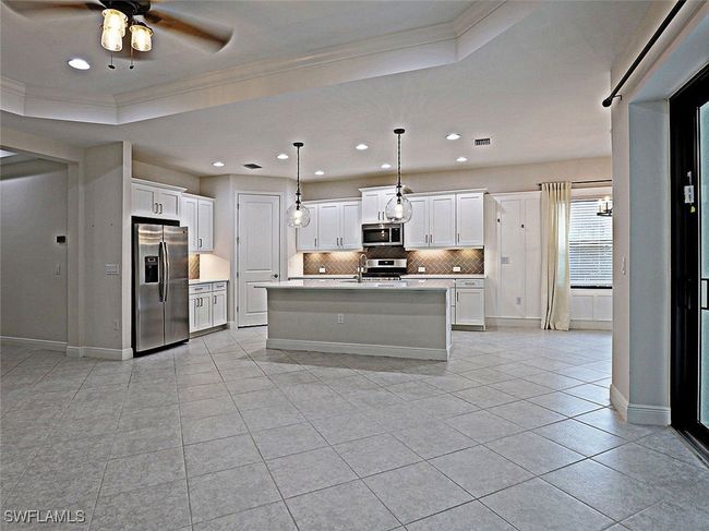 Kitchen featuring appliances with stainless steel finishes, ornamental molding, decorative backsplash, a ceiling fan, and light countertops | Image 5