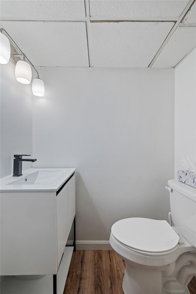 Half bathroom featuring toilet, vanity, and wood finished floors | Image 38