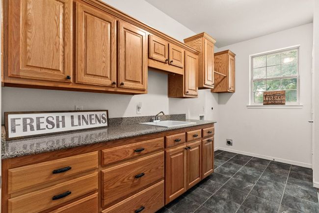 Kitchen with brown cabinetry, a sink, and baseboards | Image 21