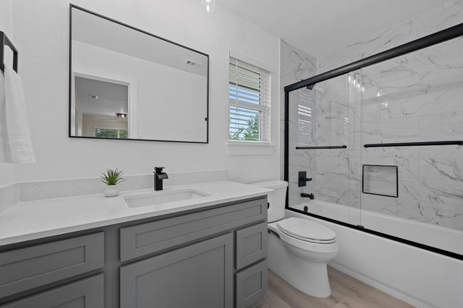 Full bathroom featuring visible vents, combined bath / shower with glass door, toilet, wood finished floors, and vanity | Image 16