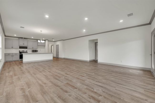 Unfurnished living room with crown molding, visible vents, baseboards, and recessed lighting | Image 12