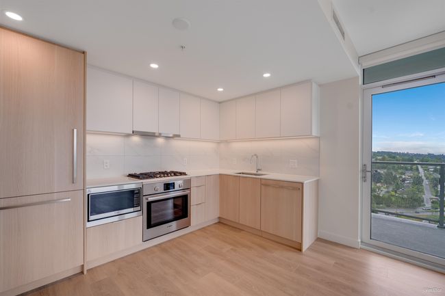 Kitchen featuring stainless steel appliances, modern cabinets, a sink, light countertops, and decorative backsplash | Image 6