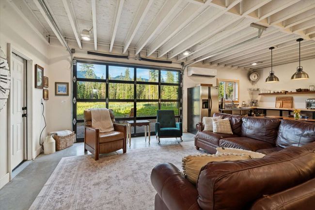 Living room with finished concrete flooring, a wall mounted AC, and healthy amount of natural light | Image 16