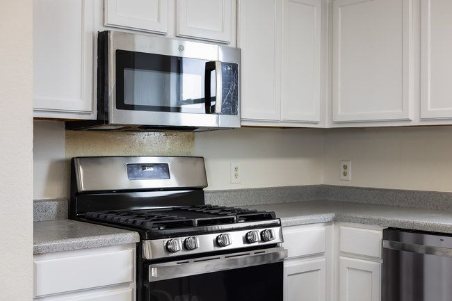 Kitchen featuring appliances with stainless steel finishes, white cabinetry, and light countertops | Image 14