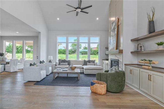 Living room with light hardwood / wood-style floors, high vaulted ceiling, a high end fireplace, and plenty of natural light | Image 7
