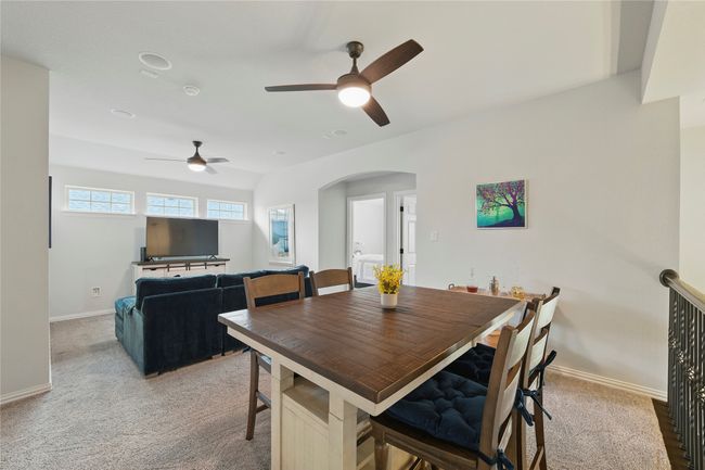Dining room with a ceiling fan, light colored carpet, and arched walkways | Image 28