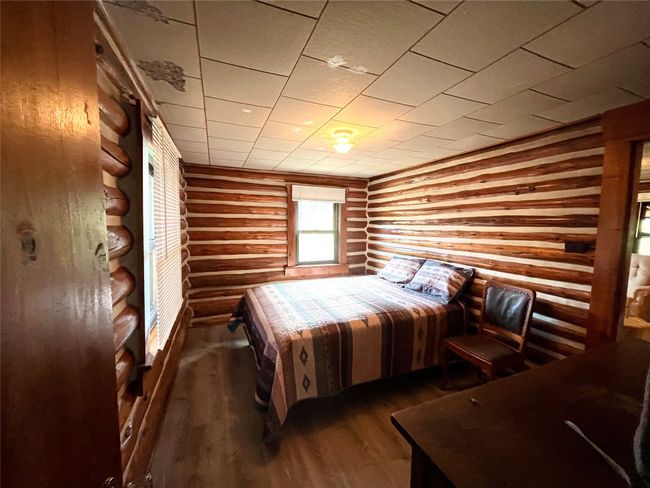Bedroom featuring rustic walls and wood finished floors | Image 11