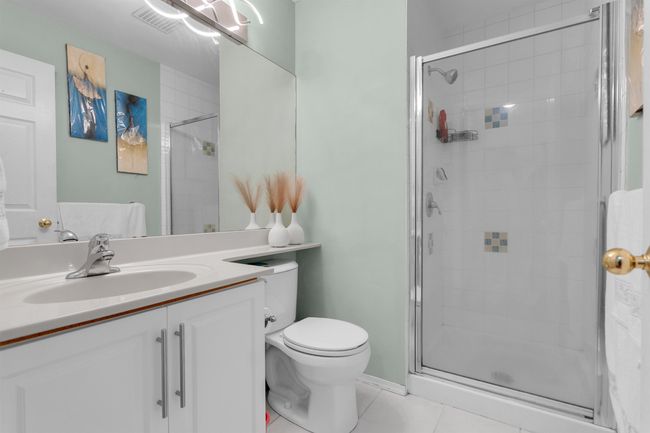 Bathroom with a stall shower, vanity, and tile patterned flooring | Image 12