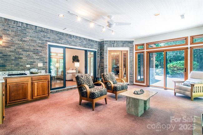 The brick wall brings a lot of warmth to this room, sliders leading to the patio | Image 16