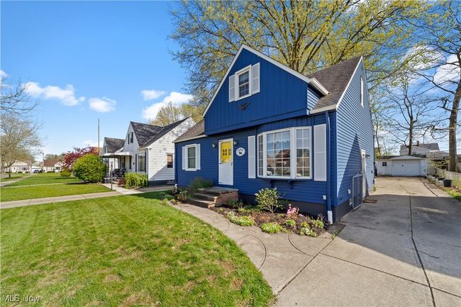 Bungalow with an outdoor structure, a front yard, roof with shingles, concrete driveway, and board and batten siding | Image 13