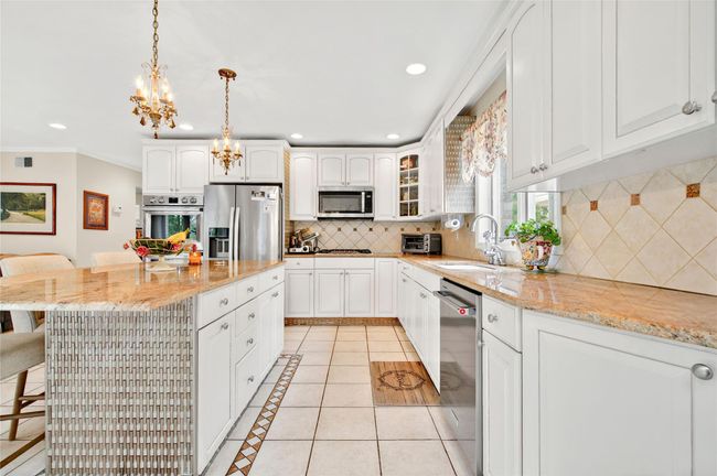 Kitchen featuring appliances with stainless steel finishes, a sink, a chandelier, a kitchen bar, and decorative backsplash | Image 18