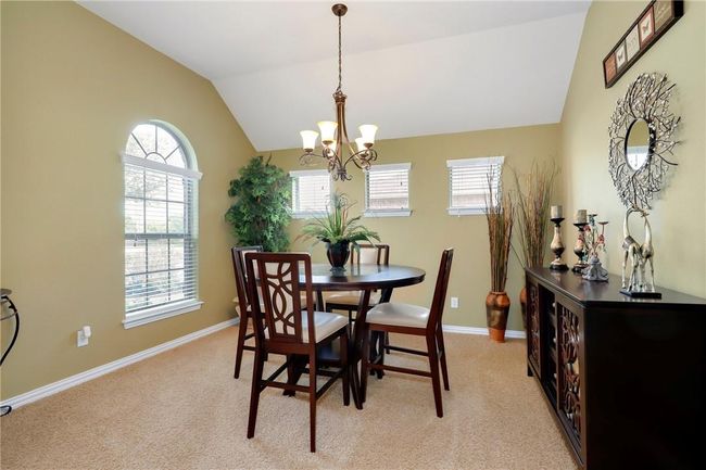 Dining room with a chandelier, vaulted ceiling, light colored carpet, and baseboards | Image 4