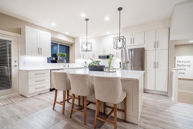 Kitchen featuring a kitchen island, decorative backsplash, white cabinets, stainless steel appliances, and light countertops | Image 8
