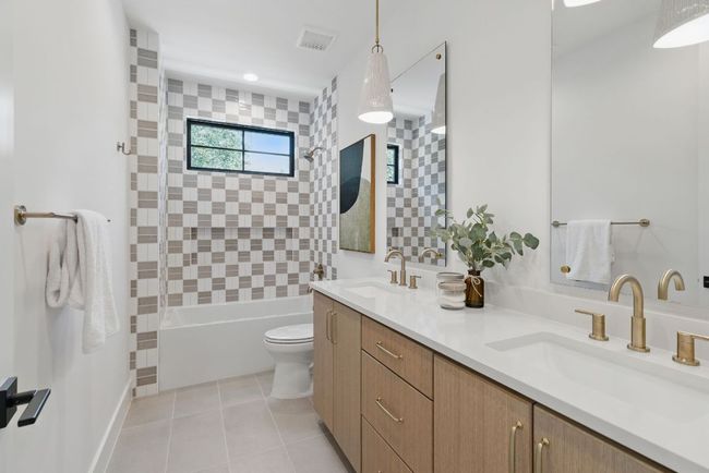 Full bath featuring toilet, double vanity, shower / bathtub combination, and tile patterned flooring | Image 20