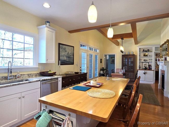 Kitchen with dark wood-style floors, a sink, beam ceiling, decorative light fixtures, and white cabinets | Image 23