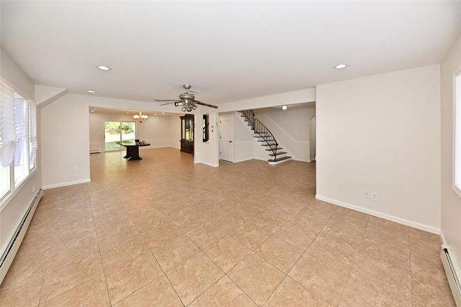 Unfurnished living room with recessed lighting, a baseboard heating unit, and stairs | Image 6