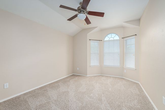 Carpeted empty room featuring a ceiling fan and lofted ceiling | Image 24