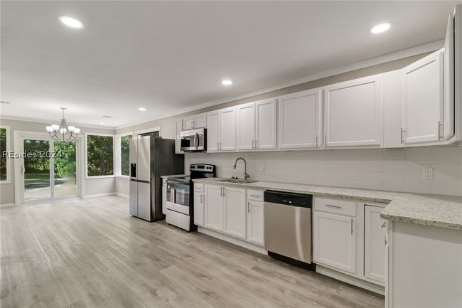 Kitchen with white cabinets, stainless steel appliances, light hardwood / wood-style floors, and decorative backsplash | Image 18