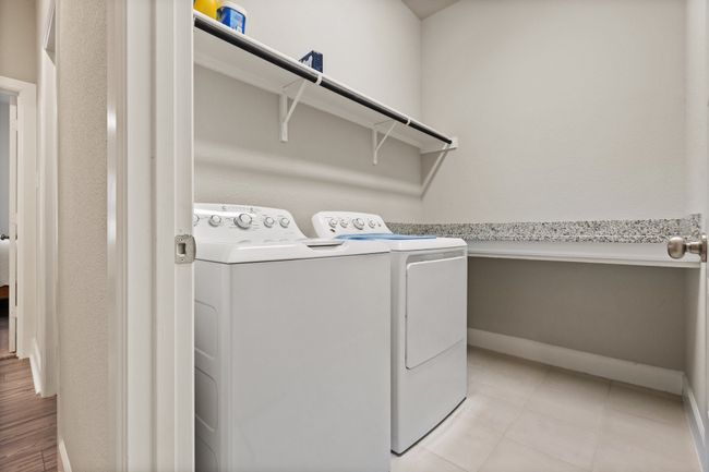 Large laundry room with full size washer and dryer (top loading) as well as a large folding table and hanging area for laundry | Image 8