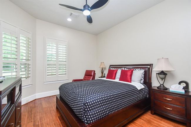Downstairs guest bedroom or Mother-in-Law suite with rustic wood flooring and plantation shutters connected to the full bath. | Image 26