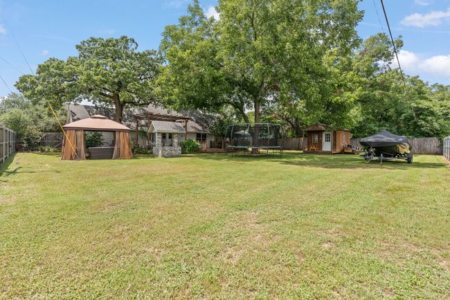 Fenced backyard with a storage shed, a trampoline, and a gazebo | Image 28