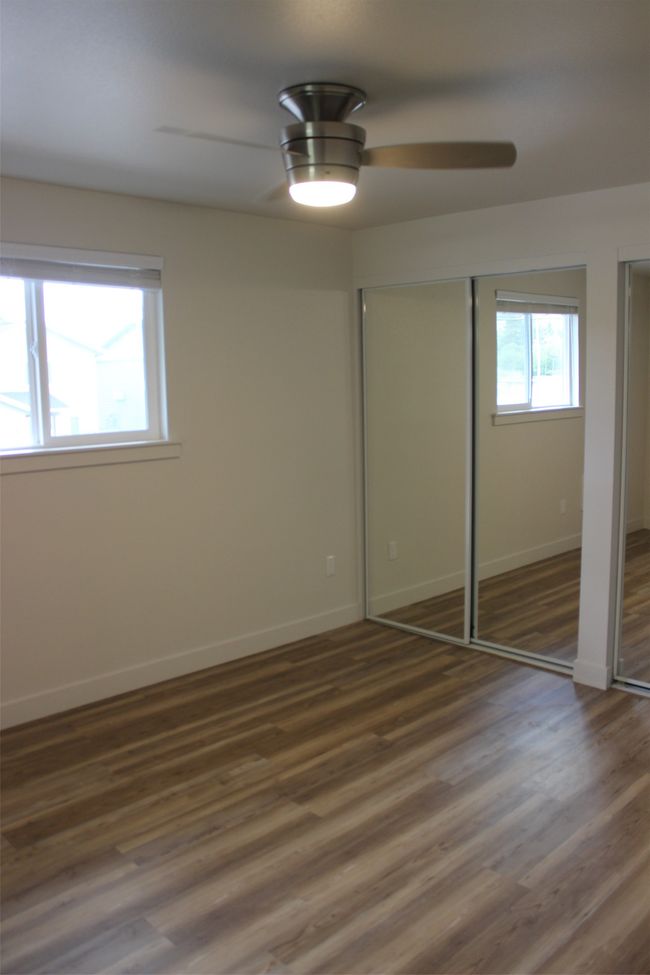 Unfurnished bedroom featuring two closets, wood finished floors, and a ceiling fan | Image 13