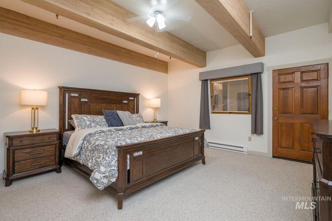 Bedroom with beamed ceiling, light carpet, baseboard heating, and a ceiling fan | Image 8
