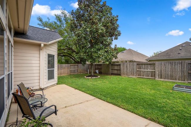 Step outside to the back patio, where you'll find gutters for added protection, a raised flower bed perfect for gardening, and a beautiful tree that provides shade and enhances the backyard’s appeal. | Image 33