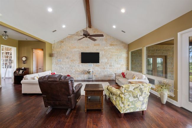 Living room featuring ceiling fan, visible vents, dark wood-style floors, and vaulted ceiling with beams | Image 4