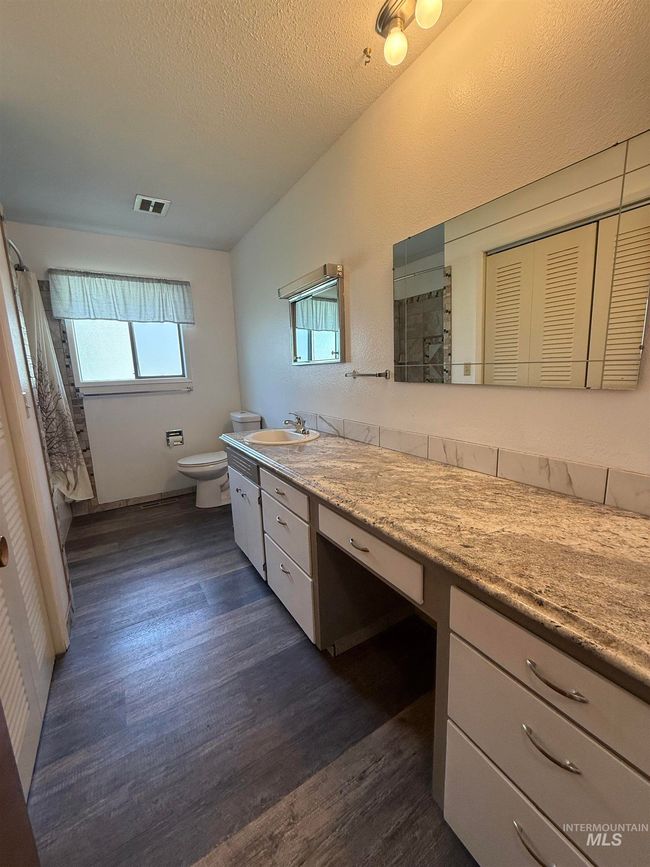 Bathroom featuring wood finished floors, vanity, a shower, and a textured ceiling | Image 22