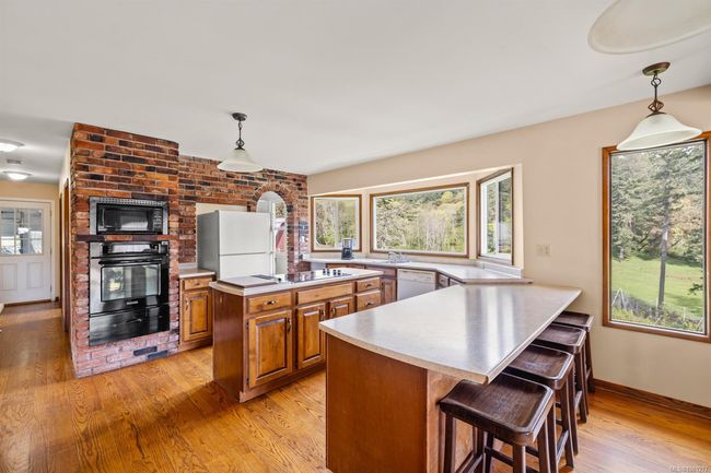 Kitchen featuring black appliances, a warming drawer, brown cabinetry, and light countertops | Image 10
