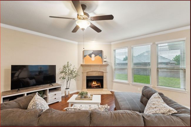 Living room featuring ceiling fan, a fireplace, crown molding, and dark wood finished floors | Image 5