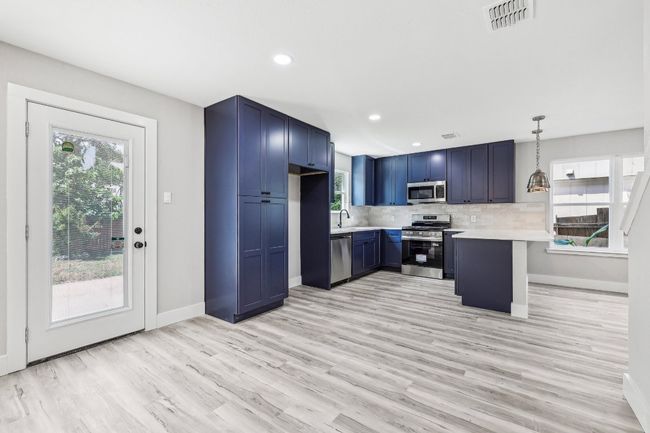 Kitchen featuring stainless steel appliances, blue cabinetry, light countertops, a peninsula, and baseboards | Image 14