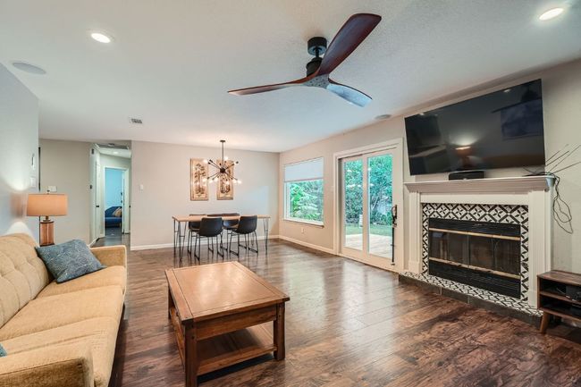 Living room featuring a ceiling fan, wood finished floors, a tiled fireplace, a chandelier, and recessed lighting | Image 11