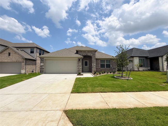 View of front of home featuring an attached garage, driveway, a front lawn, brick siding, and roof with shingles | Image 4