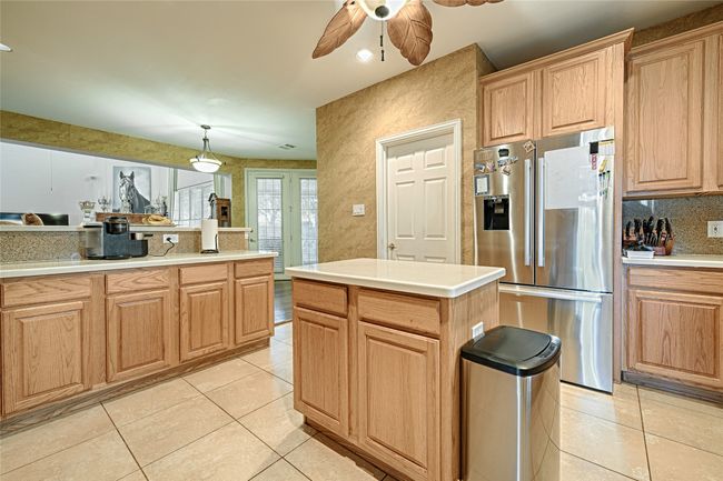 Kitchen featuring stainless steel refrigerator with ice dispenser, tasteful backsplash, light countertops, light brown cabinetry, and light tile patterned flooring | Image 27