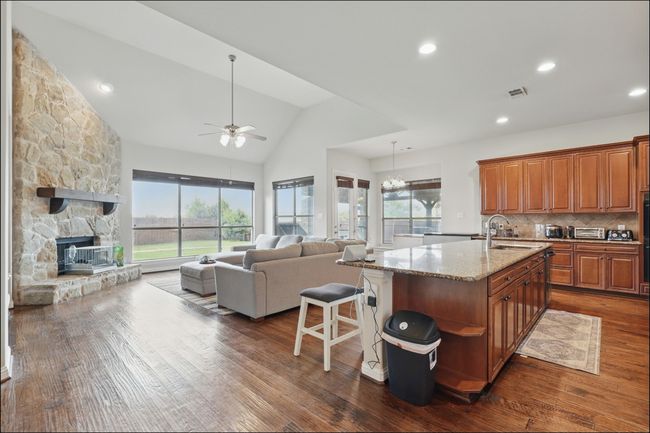 Kitchen featuring arched walkways, light stone counters, backsplash, dark wood-style floors, and recessed lighting | Image 10