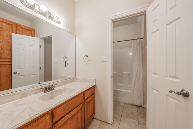 Upstairs shared split bathroom featuring tile patterned floors, vanity, and shower / bath combo | Image 10