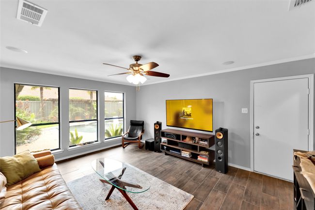 Living room with dark wood finished floors, ceiling fan, and ornamental molding | Image 7