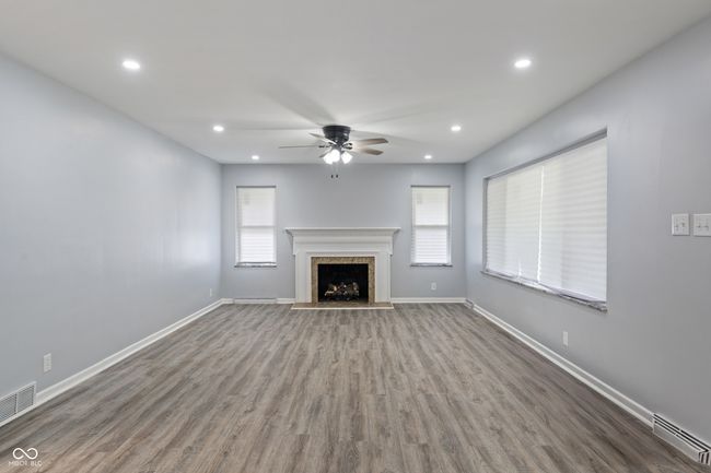 unfurnished living room with ceiling fan, wood finished floors, a fireplace, baseboards, and recessed lighting | Image 5