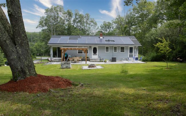 Back of property with an outdoor fire pit, a patio area, a lawn, and a chimney | Image 5