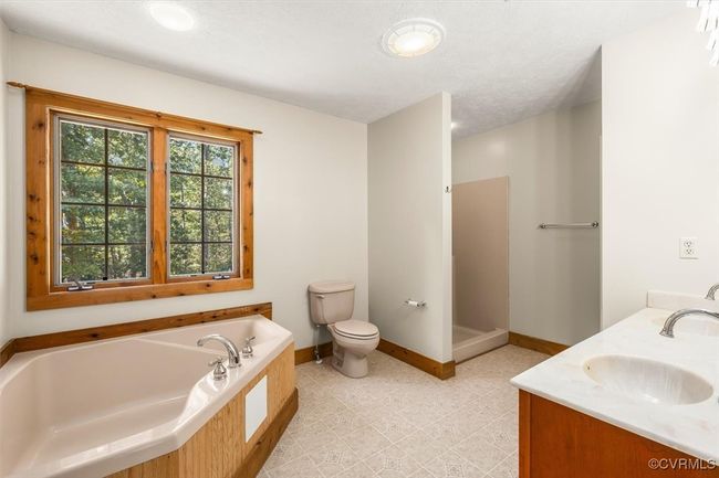 Bathroom featuring a textured ceiling, vanity, toilet, and a bathing tub | Image 46