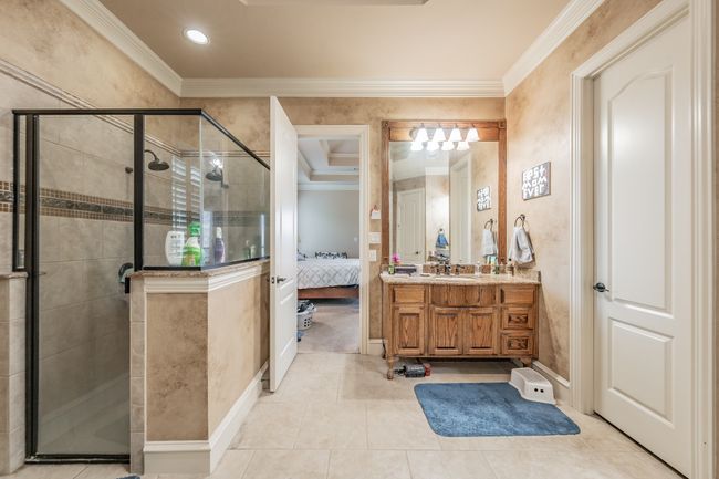 Full bath featuring ornamental molding, vanity, a shower stall, ensuite bath, and tile patterned flooring | Image 24