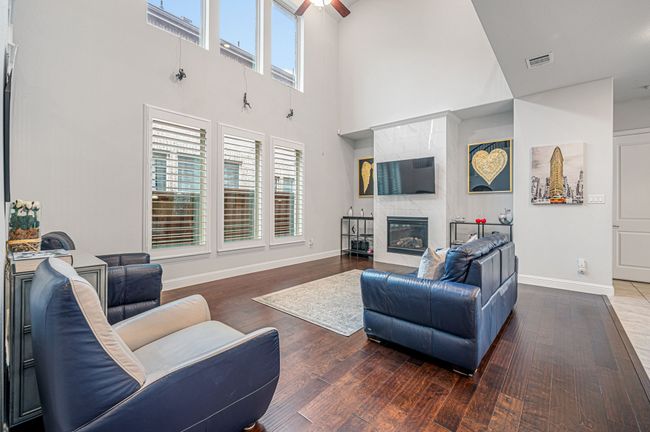 Living area with a two-story high ceiling, a premium fireplace, an abundant amount of sunlight, and wood finished floors | Image 17